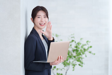 ノートパソコンを持って呼びかける若いビジネスウーマン