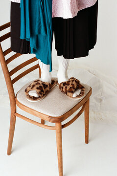 Person standing on a chair and wearing leopard-print slippers