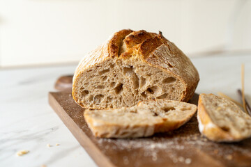Crispy sourdough bread sits beside a glass jar filled with active starter, accompanied by a rustic...