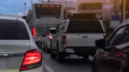 Abstact traffic jam with several vehicles lined up on a road. Close up car with its tail lights illuminated. Traffic congestion during rush hour with environment of rainy time at eveing.