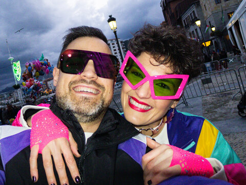 Couple wearing colorful 80s style costumes enjoying carnival party