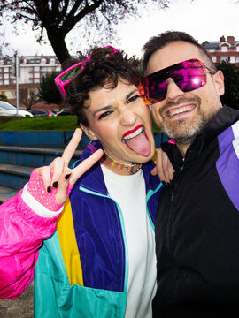Couple making victory sign and sticking out tongue wearing