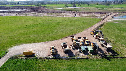  Aerial drone view of quarrying vehicles parked by a field