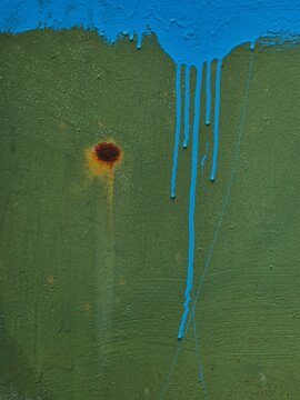 Colorful paint drips on textured green wall represent urban art