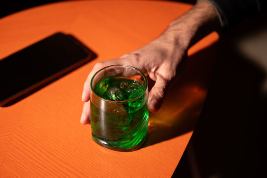 Hand holding green mint liqueur cocktail on table