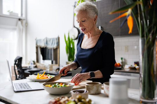 Senior Woman Preparing Food in a Modern Kitchen - Powered by Adobe