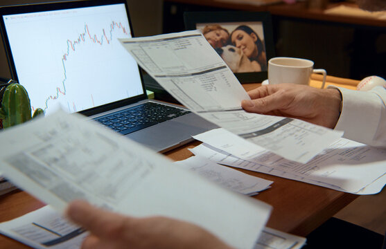 Businessman analyzing financial documents and charts on laptop