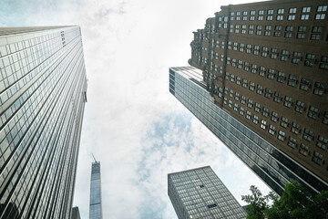 Looking up between glass and brick towers in Midtown New York City. The cloudy sky adds contrast to the vertical architectural lines.