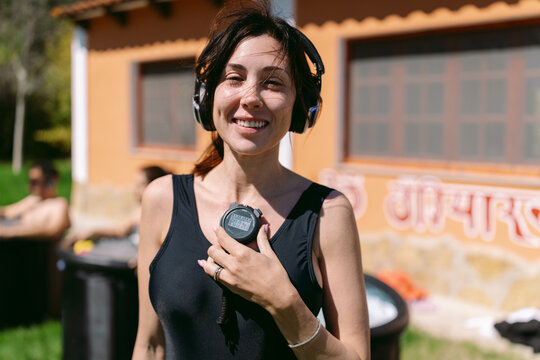 Smiling trainer with stopwatch and headphones