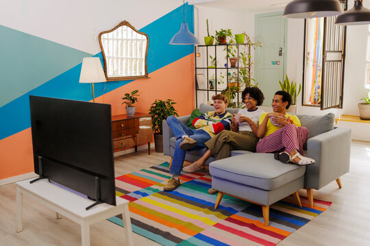 Group of roommates watching tv in colorful living room