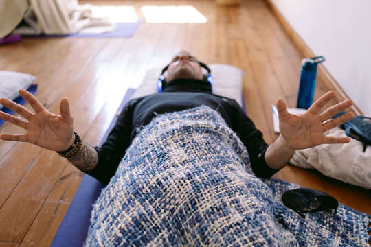 Man meditating with headphones and blanket