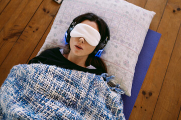 Young woman relaxing with eye mask and headphones,