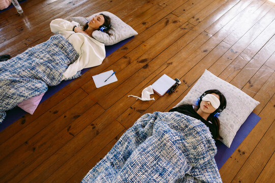 Women relaxing on yoga mats listening to guided meditation