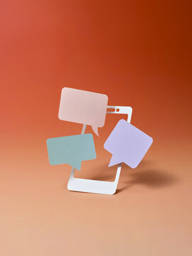 Cut-out phone with speech bubbles signifies digital conversation