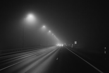 Traveling slowly down an empty highway through dark fog under dim streetlights at night, Traveling slowly down an empty highway on a dark foggy night