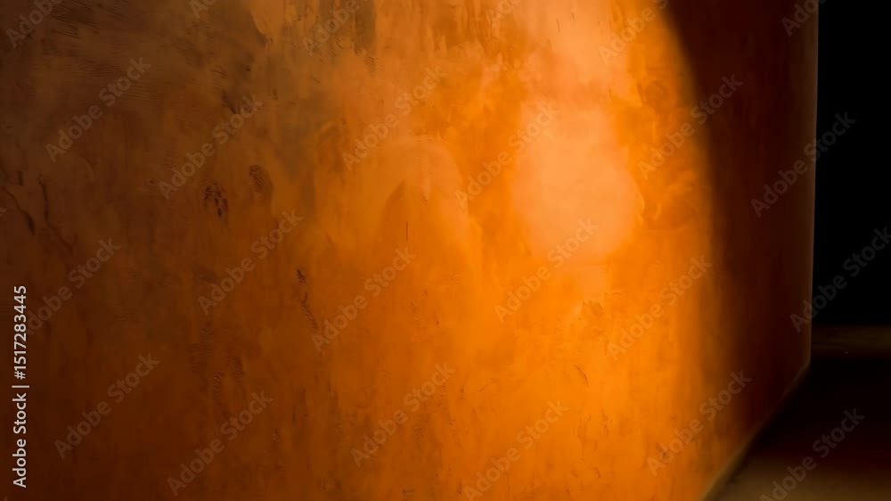 Poster moving light patterns on a textured orange plaster wall creating a warm abstract background.