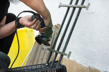 Using angle grinder to remove rust from old metal security gate