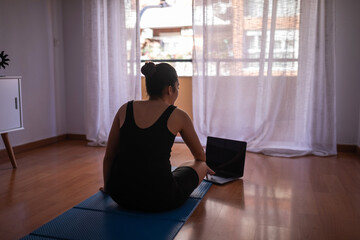 woman doing guided yoga with laptop at home