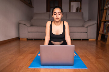 woman doing guided yoga with laptop at home