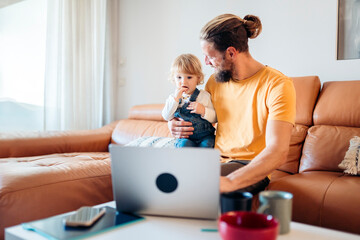 Father working from home while taking care of his child