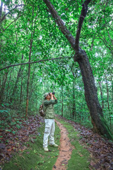 Hikers with backpacks walking on path in forest holding binoculars
