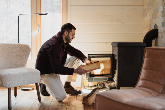 Man Preparing a Cozy Fireplace in a Warm and Modern Living Room