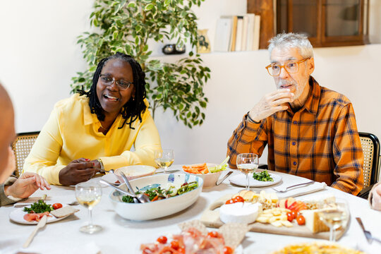 Diverse senior friends gathered together around dining table