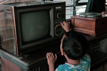 A boy is looking at an antique TV with a nostalgic, retro lifestyle feel.