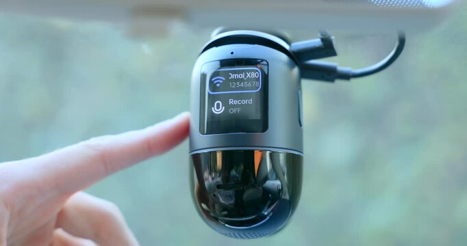Close-up shot of a modern dashcam being activated, displaying ADAS and remote video functions, highlighting advanced car safety and surveillance technology in action