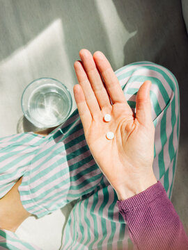 Hand Holding Pills and Glass of Water