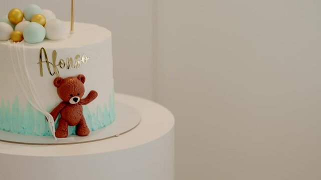 Custom baby cake with teddy bear and blue gold balloon decor featuring name Afonso in icing