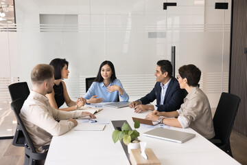 Professional team take part in meeting in office boardroom. Five businesspeople sit around...