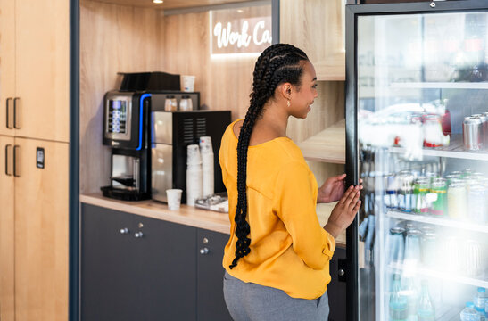 Woman choosing beverage in modern office break area
