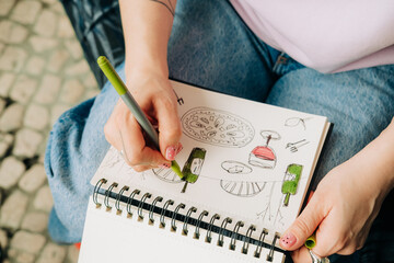 Artist coloring wine and food sketches in notebook with green marker