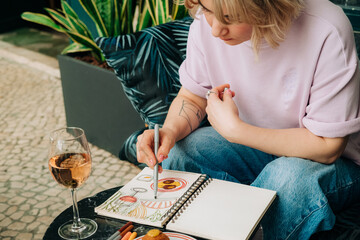 Female artist drawing food and drink scene at outdoor cafe
