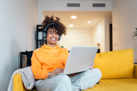 Young woman working from home on laptop and wearing headphones.
