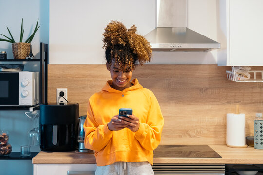 Young woman using smartphone in modern kitchen