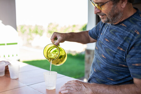 senior man serving lemonade on porch.