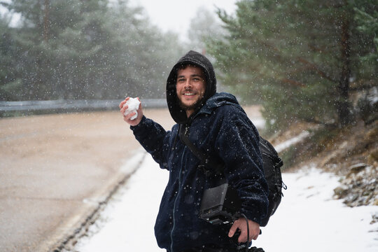Young man throwing snowball during snowfall