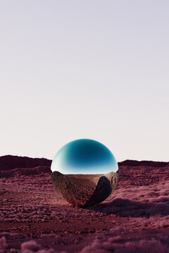 Reflective Sphere in a Vast Red Desert Landscape at Sunset