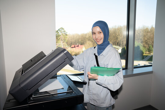 Woman Wearing Hijab Smiling While Using Office Copier

