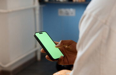 Doctor using smartphone with green screen in hospital room