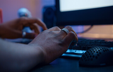 Gamer playing online video game using rgb keyboard and mouse