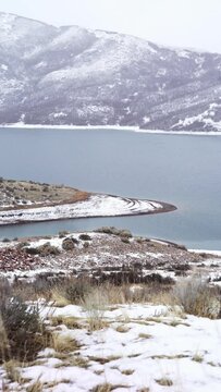 Snow covered shoreline and mountain landscape surrounding cold lake utah slc county
