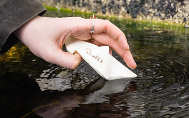 Starting to destroy a paper boat with the word doubt