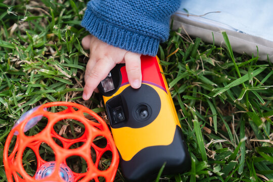 Baby hand holding colorful disposable camera