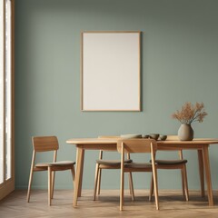 Minimalist dining room with light wood table and chairs, sage green walls, and a blank framed poster above. Sunlight streams in from a nearby window
