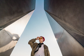 Person in red sailor-style hat standing between tall metal structures