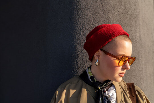 Woman in red knit hat and sunglasses looking sideways