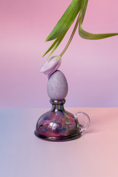 Vibrant easter egg balanced with floral elements on a glass base
